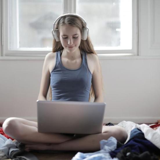 Ung kvinde sidder på gulvet med sin bærbare computer