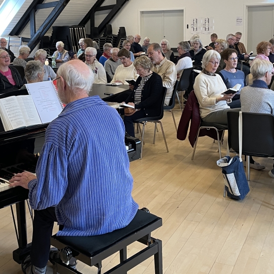 Hans Holm ved Flygelet og folk som synger
