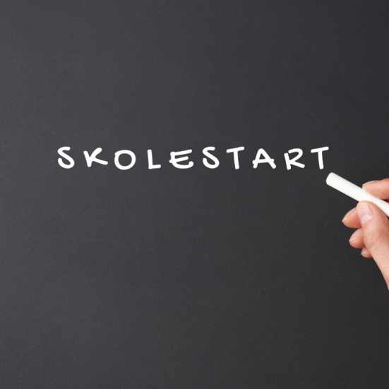 Hånd der skriver skolestart på en tavle
