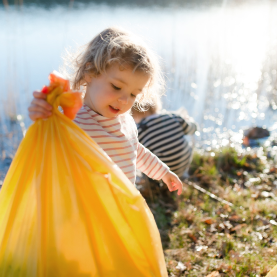 Barn i naturen holder en skraldesæk