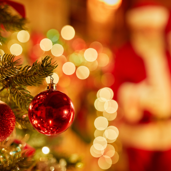 Julekugler på en juletræsgren og en sløret julemand i baggrunden