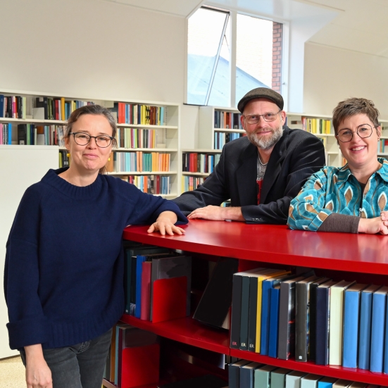 Britt, Frederik og Anne ved rød bogreol