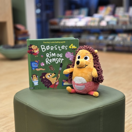 Børste-bamsen og bogen "Børstes rim og remser" på en grøn puf på Kjellerup Bibliotek
