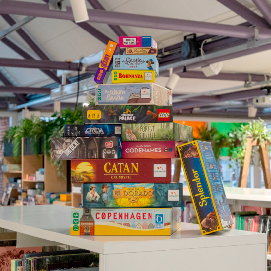 En stak af brætspil stående på en bogreol på Silkeborg Bibliotek. 