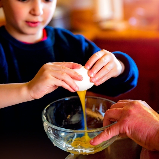 barn slår et æg ud i en skål