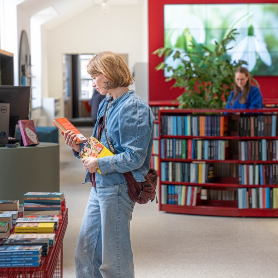Kvinde der læser på bagsiden af en bog på Silkeborg Bibliotek
