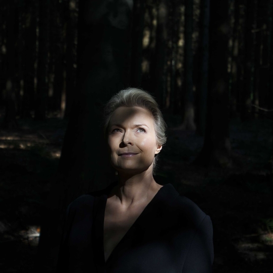 Forfatterportræt Helle Helle: står i lysningen i en skov