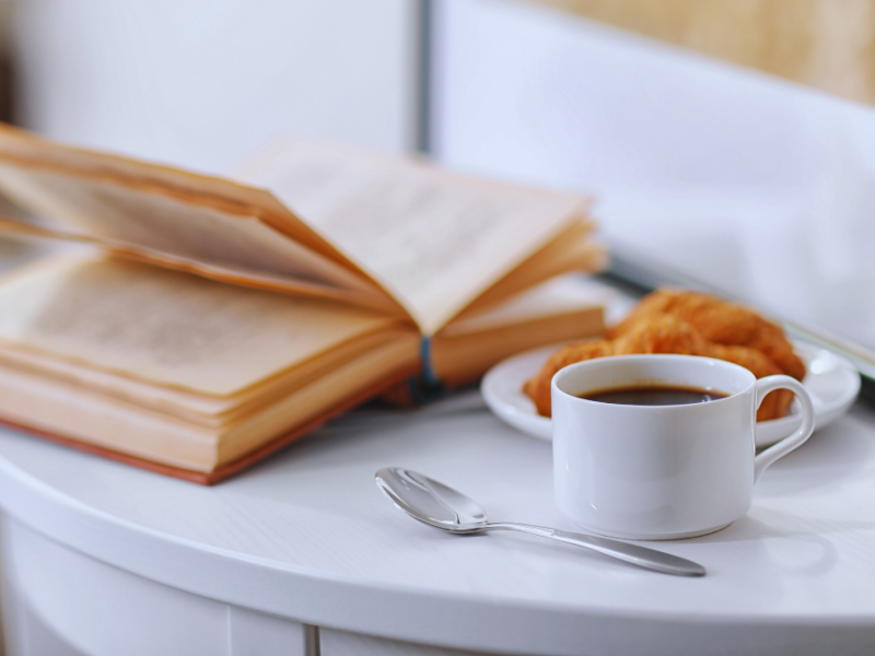 En åben bog, en kop kaffe og morgenbrød