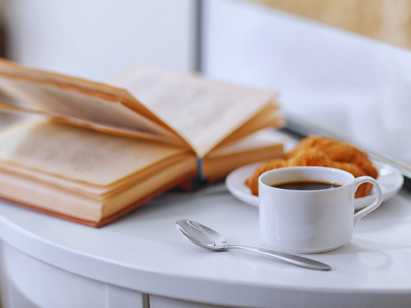 En åben bog, en kop kaffe og morgenbrød