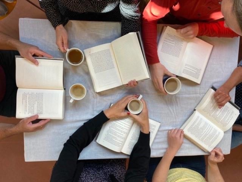 Billede af 5 personer der holder en bog omkring et bord