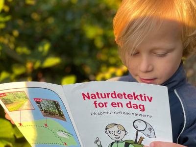 Dreng sidder med en folder, der hedder Naturdetektiv for en dag