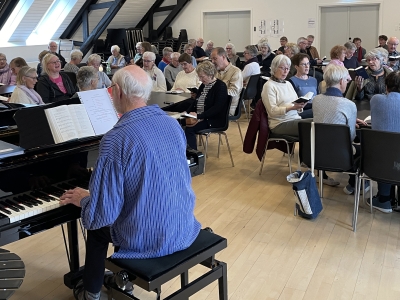 Hans Holm ved Flygelet og folk som synger