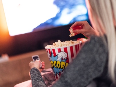 Pige spiser popcorn foran tv