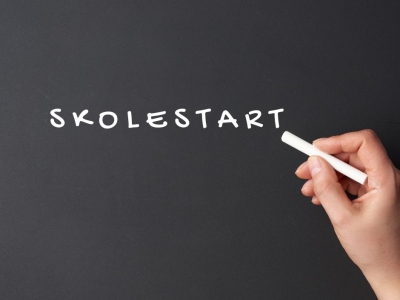 Hånd der skriver skolestart på en tavle