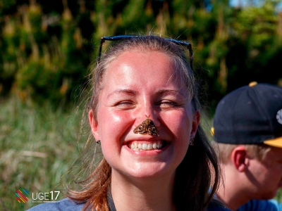 En smilende kvinde med en sommerfugl siddende på næsen.