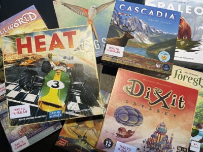 BIllede af forskellige brætspil i en bunke: Heat, Cascadia, Paleo, DiXit, Wingspan og andre man ikke kan læse titlerne på. 