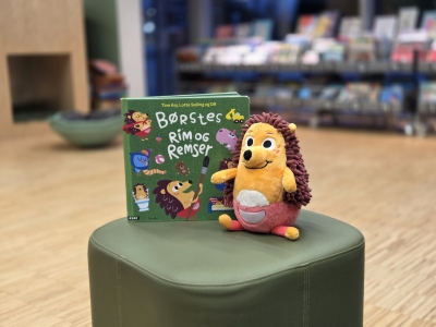 Børste-bamsen og bogen "Børstes rim og remser" på en grøn puf på Kjellerup Bibliotek