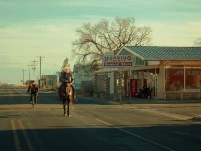 mand rider på hest gennem en lille amerikansk by