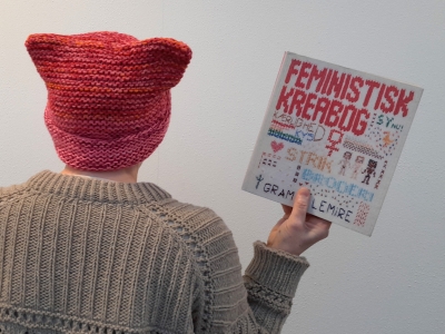 Person set bagfra med strikhue og trøje og kreabog i hånden