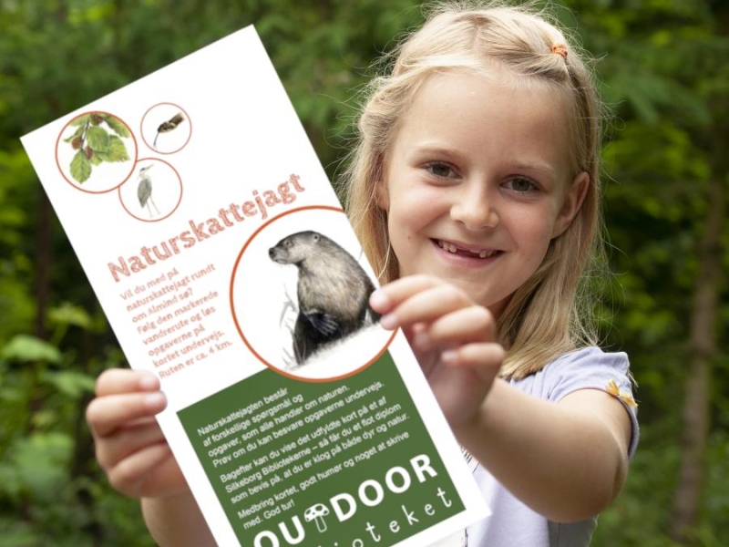 Pige holder en folder med skattejagt frem mod kameraet