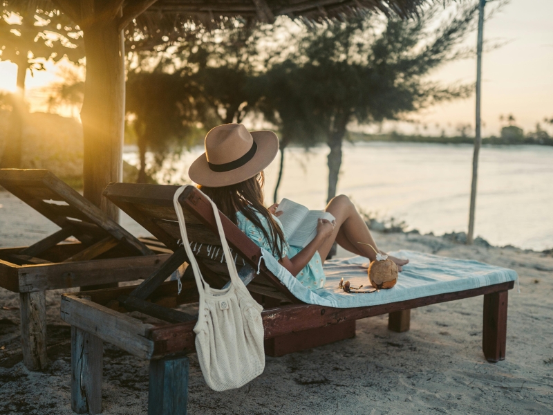 Kvinde med bog på liggestol ved vandet