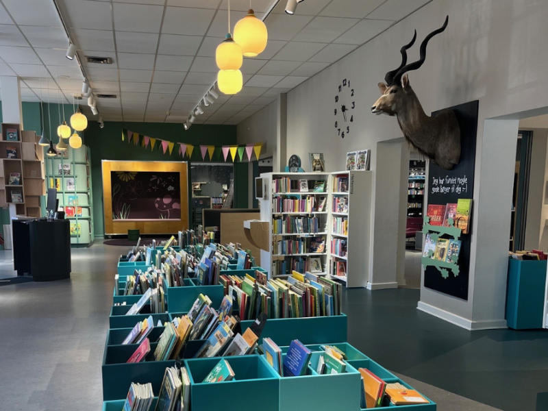 Børnebiblioteket på Silkeborg Bibliotek. Kasser med bøger, et udstoppet Kudu-hoved på væggen og en flagranke i baggrunden. 