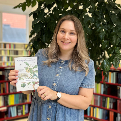 Billede af formidler i biblioteksrummet, der holder romanen "Gartneren og Døden" af Georgi Gospodinov