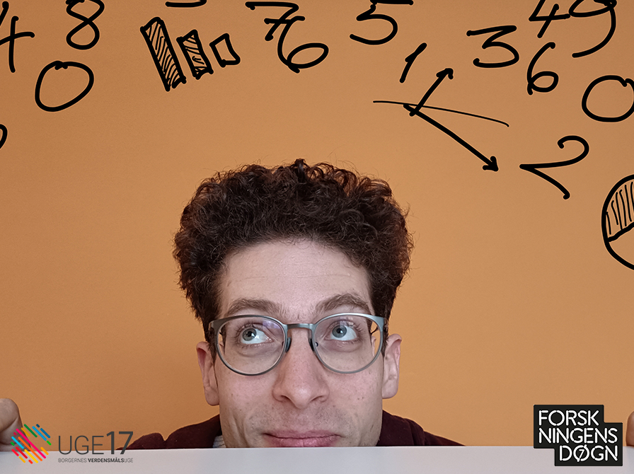 Mand med briller og krøllet kort hår kigger op på sort skrift med tal og grafer