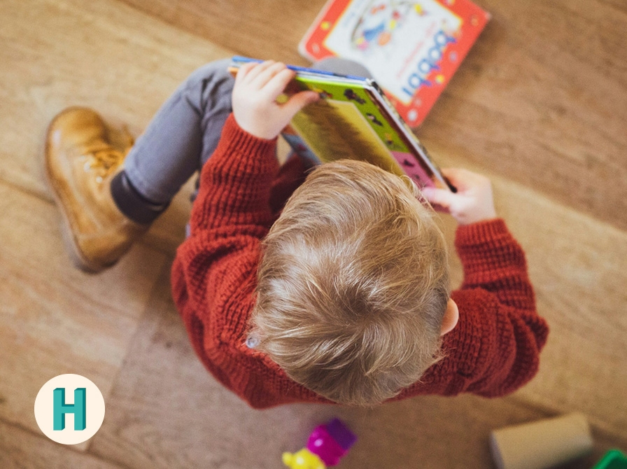 Et barn med bøger set fra oven