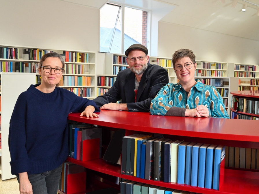 Britt, Frederik og Anne ved rød bogreol