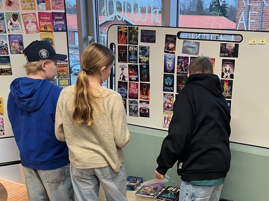 3 børn foran tavler med bogforsider