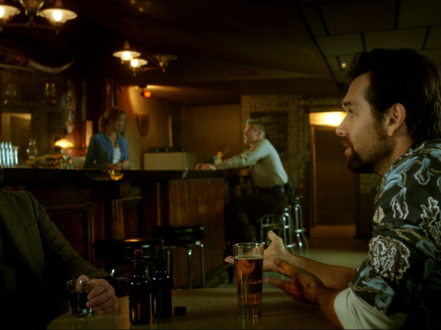 to mænd sidder på en bar og snakker intenst