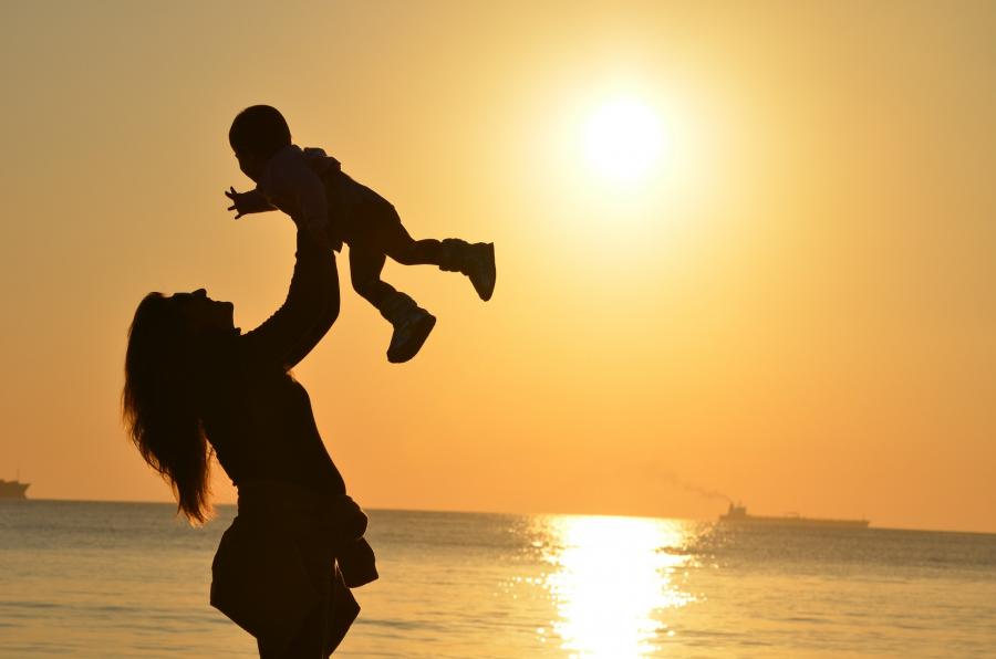 Mor svinger sit barn i solnedgang