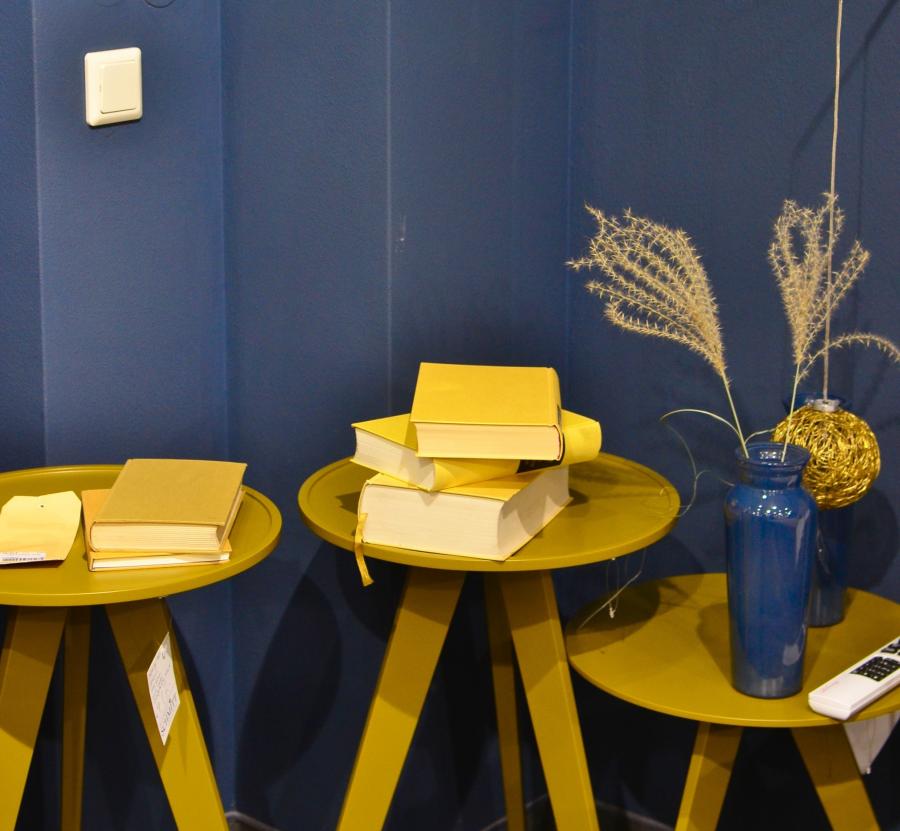 gule bøger på lave borde, blå baggrund