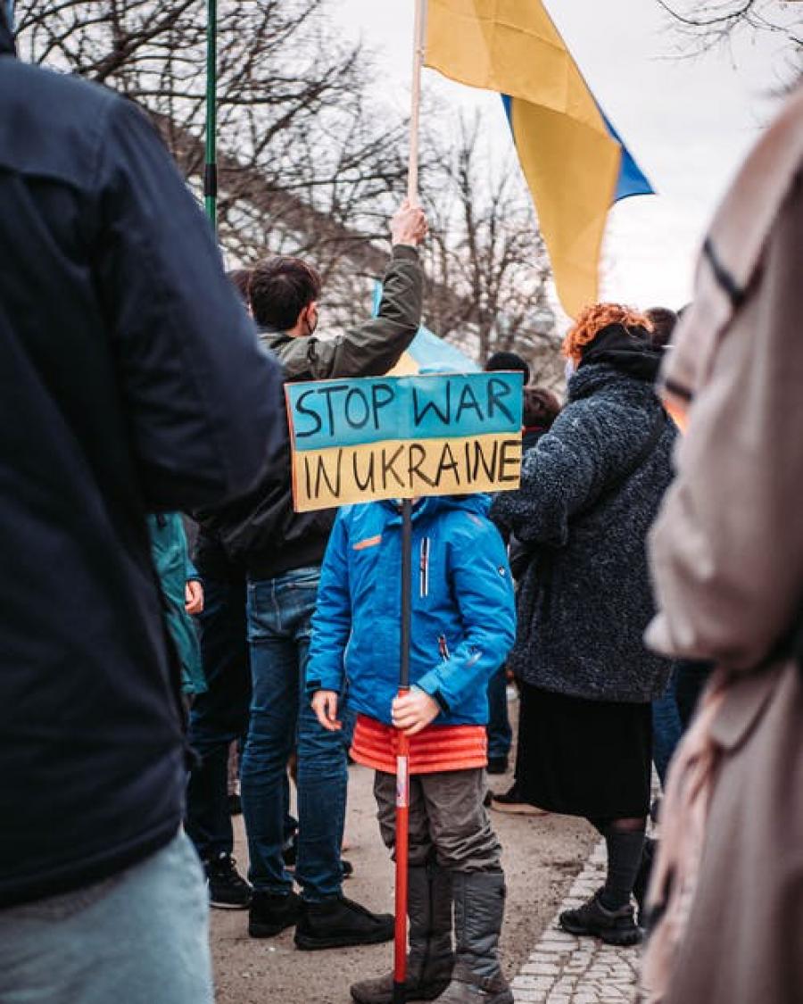 Gruppe af mennesker. Her står en dreng med et skilt: stop war in ukraine