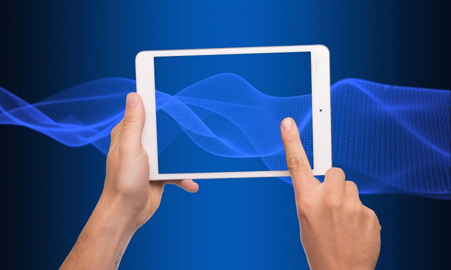 En hånd holder en tablet og peger med en finger på skærmen, blå baggrund